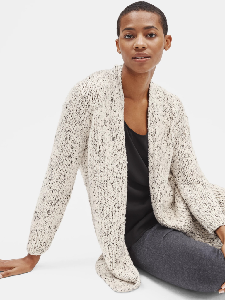 A woman wearing a long neutral cardigan styled casually